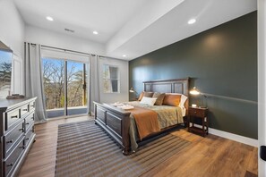 Ein Schlafzimmer mit einem großen Bett, einem Schminktisch, einem Nachttisch und einem Fenster mit Jalousien.