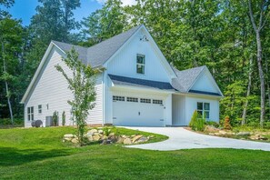 A single-story house with a garage, surrounded by a well-maintained lawn and trees. - Cloudland Summit | Hot Tub + Grill | Dog Friendly (Rising Fawn)