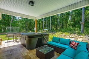 Eine Außenpatio mit Whirlpool, Sitzgelegenheit und Grill.