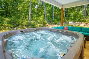 A hot tub with a wooden deck and a green sofa with cushions. - Cloudland Summit | Hot Tub + Grill | Dog Friendly (Rising Fawn)