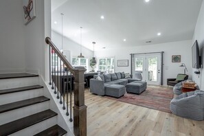 Ein geräumiger Wohnbereich mit Treppe, einem Ecksofa und einem Flachbildfernseher.