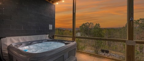 A hot tub in a covered outdoor area with a view of the landscape.