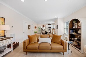 Un salon avec un canapé en cuir marron, une petite table d’appoint et une bibliothèque.