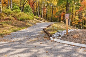 A gravel path leading through a forested area with a sign indicating a hiking trail. - Bluebird Cottage | Near Downtown | Walking Trails! (Chattanooga)