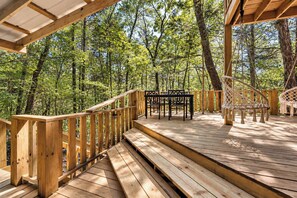 A wooden deck with a table and chairs, surrounded by trees.