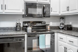 A modern kitchen with a microwave, stove, dishwasher, and coffee maker. - Lake Hills Landing | Family Friendly+Hot Tub+EV (Trenton)