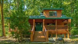 A wooden cabin with a porch, a front door, and a small outdoor grill. - Hideaway Lodge | Rustic W/ Hot Tub! Pet Friendly (Trenton)