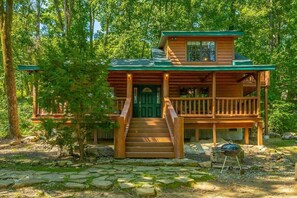 A wooden cabin with a porch, a front door, and a small outdoor grill. - Hideaway Lodge | Rustic W/ Hot Tub! Pet Friendly (Trenton)