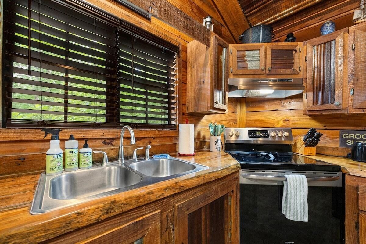 A kitchen with wooden cabinets, a stainless steel sink, and a stove.