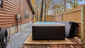 A hot tub in a wooden cabin setting with a gravel path and a wooden fence. - Hideaway Lodge | Rustic W/ Hot Tub! Pet Friendly (Trenton)