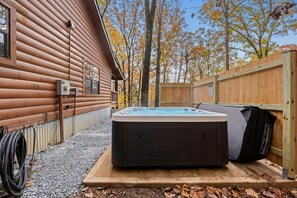 A hot tub in a wooden cabin setting with a gravel path and a wooden fence. - Hideaway Lodge | Rustic W/ Hot Tub! Pet Friendly (Trenton)