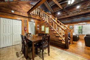 A wooden interior with a staircase, dining table, chairs, and a fire extinguisher. - Hideaway Lodge | Rustic W/ Hot Tub! Pet Friendly (Trenton)