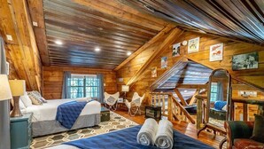 A log cabin-style room with two beds, a staircase, and a large mirror. - Hideaway Lodge | Rustic W/ Hot Tub! Pet Friendly (Trenton)