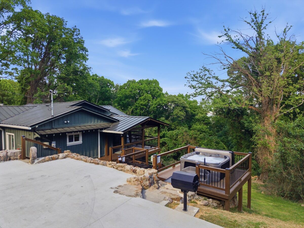 A lodge with a hot tub, a covered deck, and a stone wall.