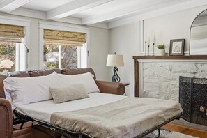 A bedroom with a bed, a lamp, a fireplace, and a window with a view of the outdoors. - The Nest: Epic Family Home w/ Rock Climbing+Slide (Chattanooga)