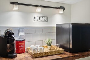 A kitchen with a coffee maker, a red Folgers coffee can, a tray with cups, and a refrigerator. - The Nest: Epic Family Home w/ Rock Climbing+Slide (Chattanooga)