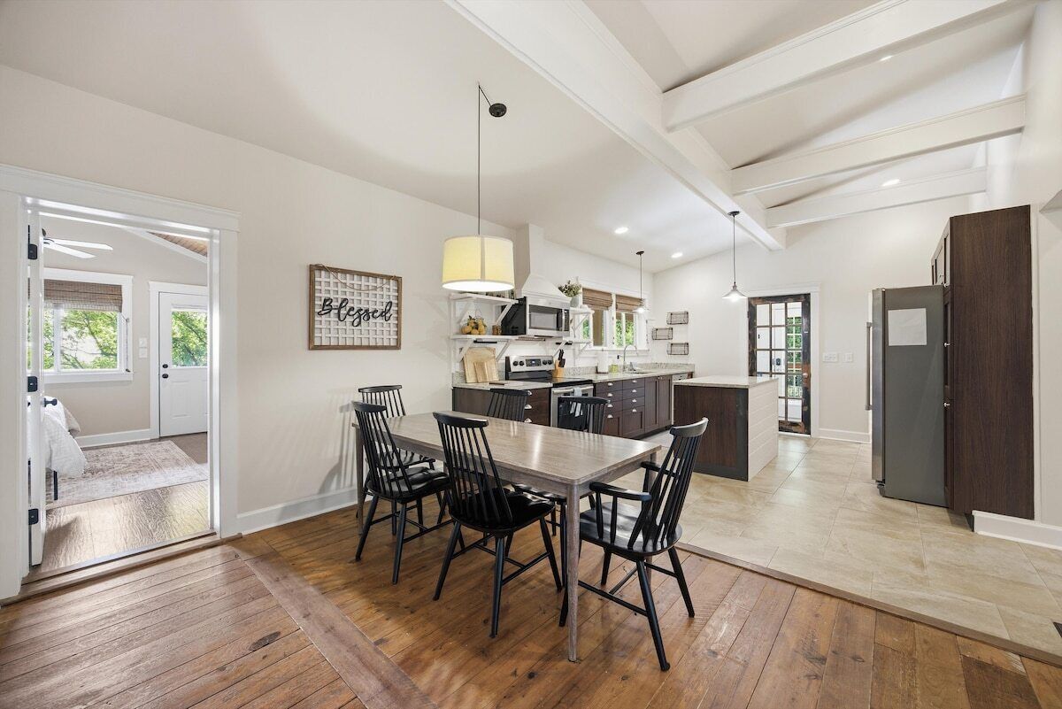 A modern kitchen with a dining area, wooden flooring, and a large island with appliances.