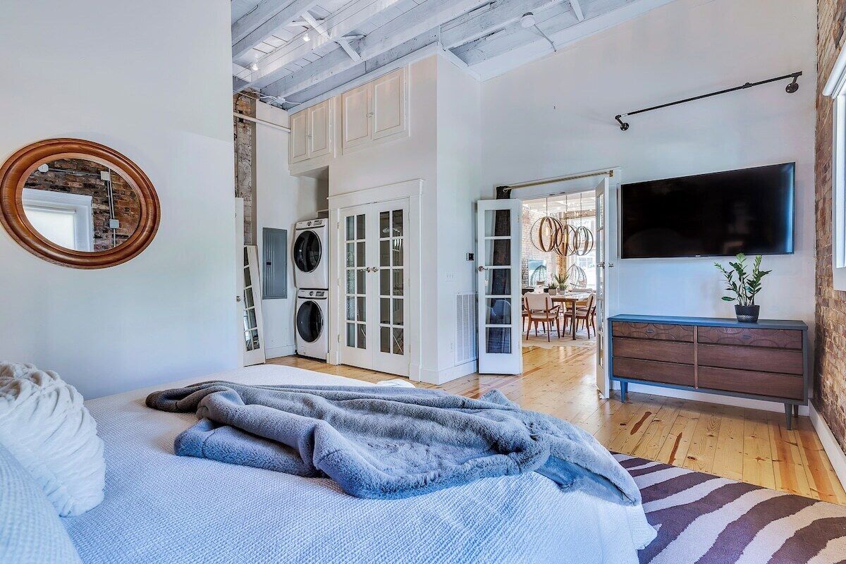 Une chambre à coucher comprenant un lit, un téléviseur, une commode et un espace dédié au linge.