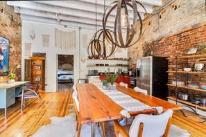 A dining area with a wooden table, chairs, and a hanging light fixture. - Saint Elmo Loft | Upscale Retreat • Near Downtown! (Chattanooga)