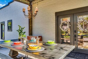 An outdoor dining area with a table set for four, potted plants, and a decorative chandelier. - Saint Elmo Loft | Upscale Retreat • Near Downtown! (Chattanooga)