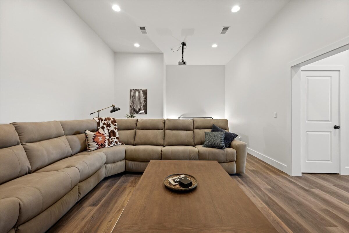 A modern living room with a sectional sofa, a coffee table, and a ceiling-mounted projector.
