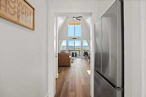 Eine moderne Küche mit einem Edelstahl-Kühlschrank, Holzboden und Blick auf eine Terrasse.