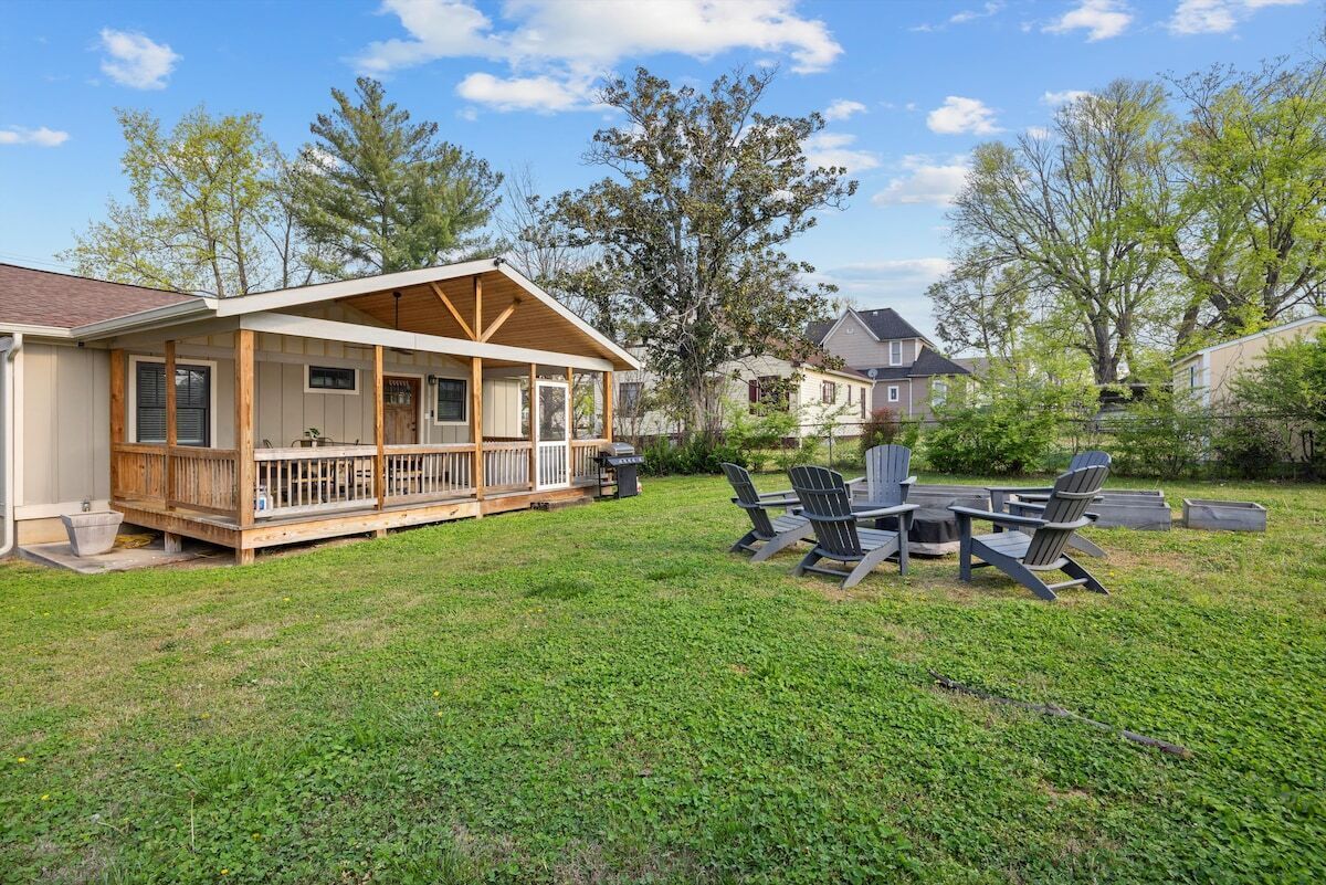 Ein Haus mit überdachter Veranda, einer Terrasse mit Gartenmöbeln und einem gepflegten Rasen.