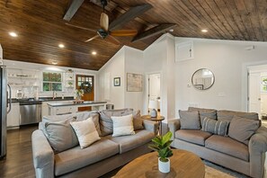 A modern living room with two grey sofas, a wooden coffee table, and a ceiling fan.
