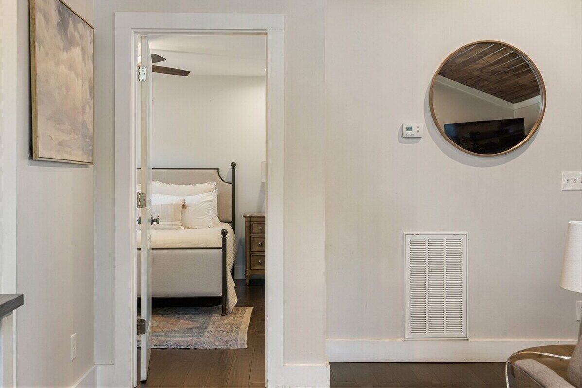 Une chambre à coucher avec un lit, une table de chevet et un miroir rond accroché au mur.