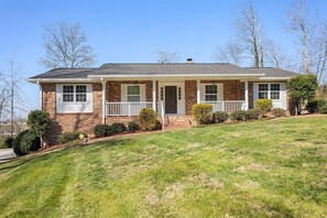 A two-story brick house with a front porch, a garage, and a well-maintained lawn. - The Wrenley Chateau | Great Location + Backyard! (Ringgold)