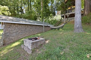 A stone building with a metal roof, a brick fire pit, and a hammock. - Lake front/Hot Tub/Game Room/Dock  Home in Lexington, NC (Lexington)