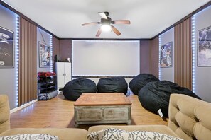 A room with a ceiling fan, bean bag chairs, a wooden coffee table, and a projector screen. - Lake front/Hot Tub/Game Room/Dock  Home in Lexington, NC (Lexington)