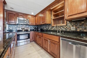 A modern kitchen with wooden cabinets, stainless steel appliances, and a tiled backsplash. - Lake front/Hot Tub/Game Room/Dock  Home in Lexington, NC (Lexington)