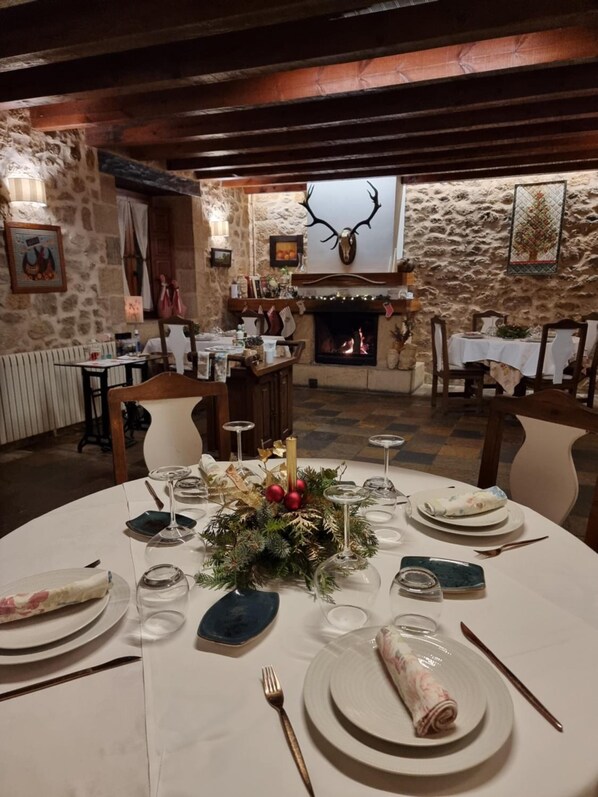A dining area with a stone wall, a fireplace, and a deer head decoration. - Posada Ribacardo (Medina De Pomar)