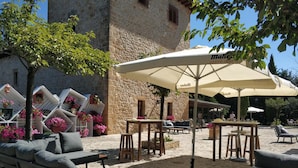 Un espace extérieur aménagé avec des tables et des chaises, entouré de murs en pierre et agrémenté de plantes en pot.