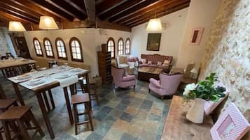 Zona de menjador amb taula preparada per a una estada, un sofà i un vas decoratiu.