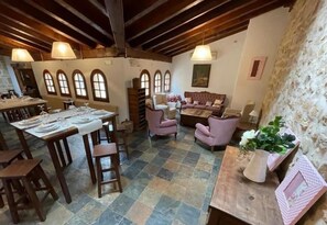 A dining area with a table set for a meal, a sofa, and a decorative vase. - Posada Ribacardo (Medina De Pomar)