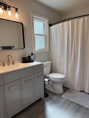 Een badkamer met een wit wastafel, toilet, douchegordijn en een raam met een geëtste glasdecoratie.