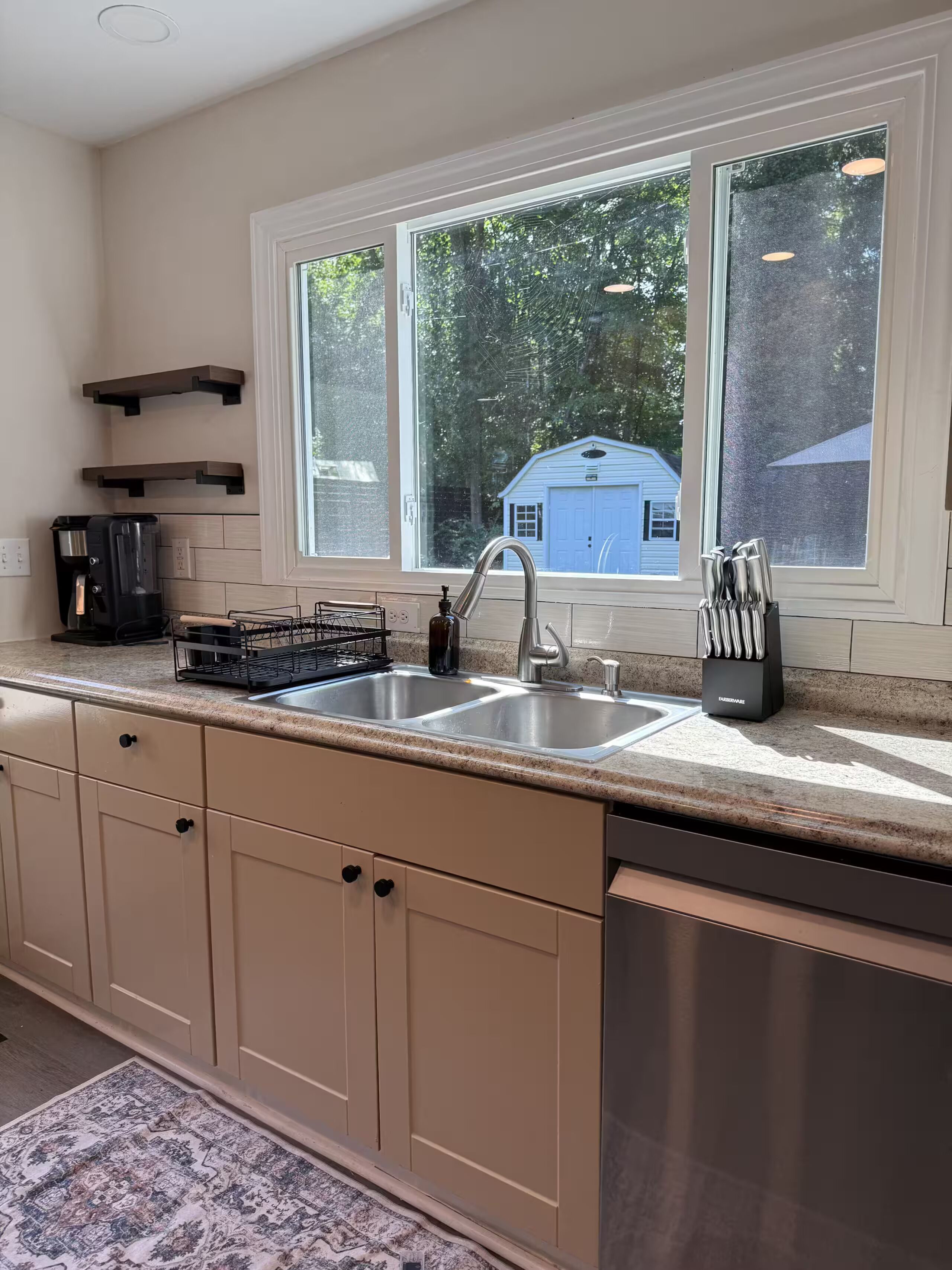 A kitchen with a double sink, a coffee maker, and a knife block.