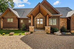 Une cabane en rondins avec une entrée en pierre, un revêtement en bois et une allée gravillonnée.