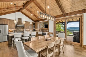 A spacious kitchen with a large island, wooden ceiling beams, and a view of the outdoors. - Love & Sunsets at Eagles Nest - hot tub, expansive mountain view, outdoor fireplace (Banner Elk)