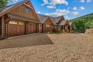 A large, multi-car garage with a gravel driveway and wooden exterior. - Love & Sunsets at Eagles Nest - hot tub, expansive mountain view, outdoor fireplace (Banner Elk)