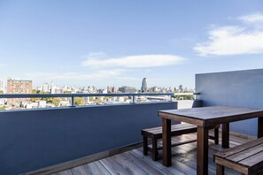 A balcony with a wooden table and chairs, overlooking a cityscape with buildings and a clear sky. - Modern Studio with Pool, Gym, and Private Grill—Palermo (Buenos Aires)