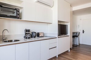 A modern kitchen with a built-in toaster, coffee maker, and a flat-screen TV. - Modern Studio with Pool, Gym, and Private Grill—Palermo (Buenos Aires)