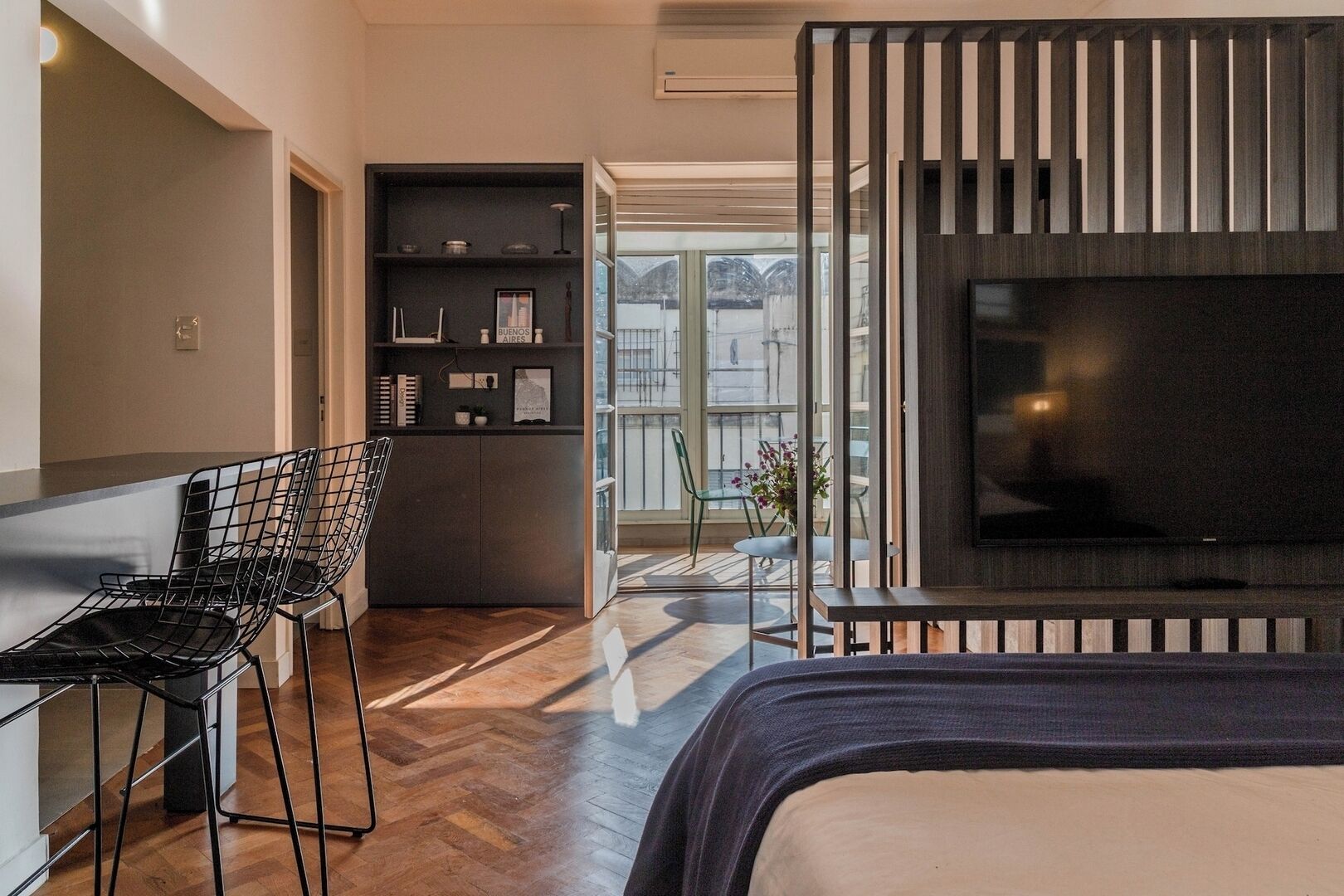 Une chambre moderne avec un grand lit, un téléviseur et un coin salon avec des fauteuils.