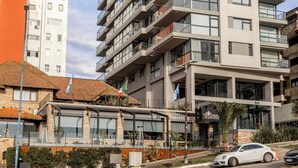 Un edificio a più piani con balconi, un ristorante al piano terra e cielo sereno.
