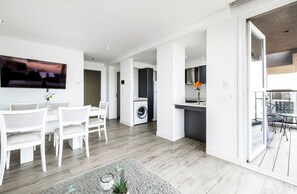 A modern living space with a dining area, kitchen, and a balcony. - Bright apartment just steps from the ocean, with a pool and gym (Mar del Plata)