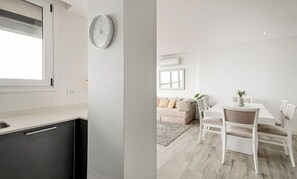 Une cuisine moderne avec une fenêtre, une horloge et un coin repas comprenant une table et des chaises.
