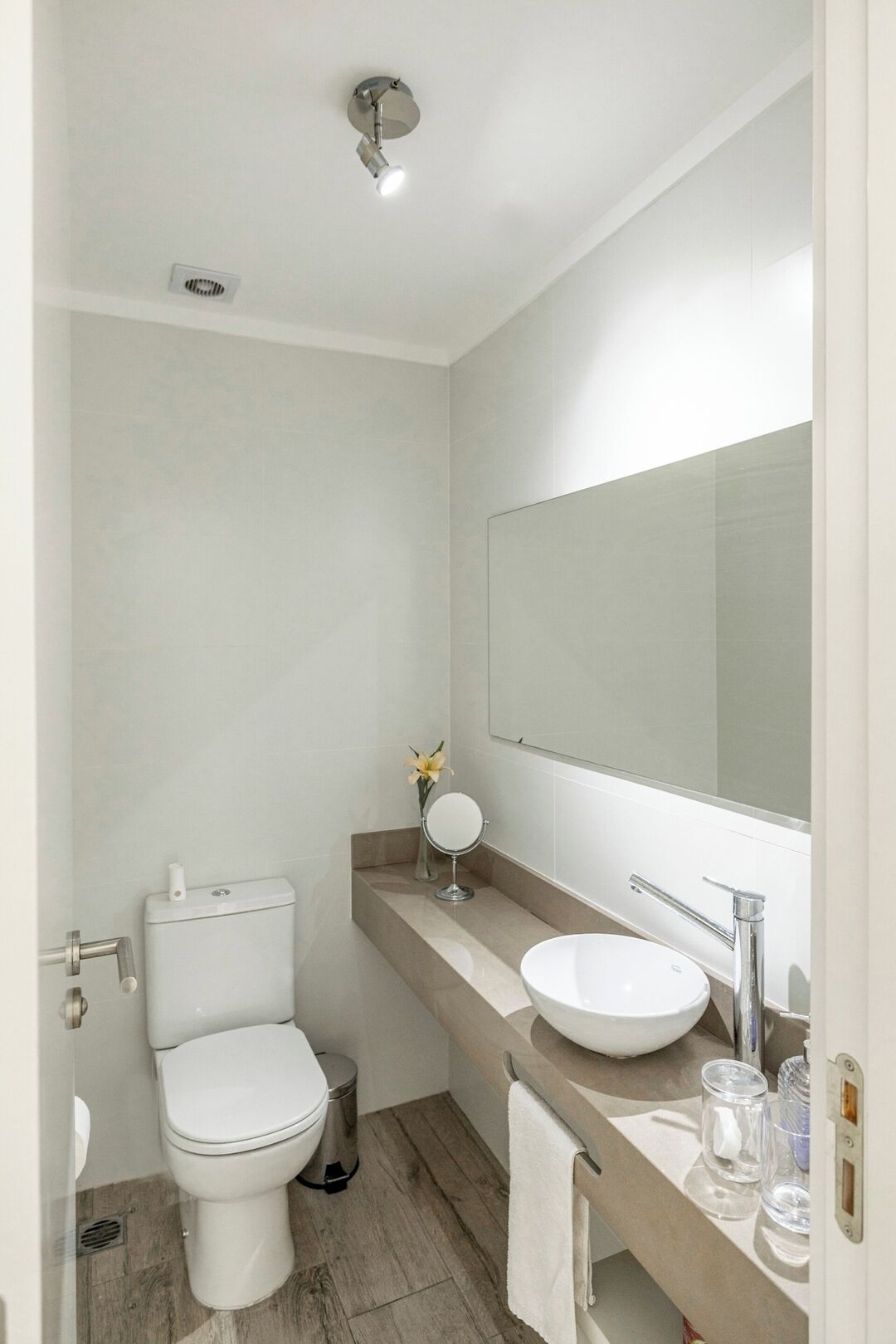 Un baño moderno con inodoro, lavamanos y espejo.