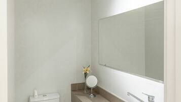 Un baño moderno con inodoro, lavamanos y espejo.